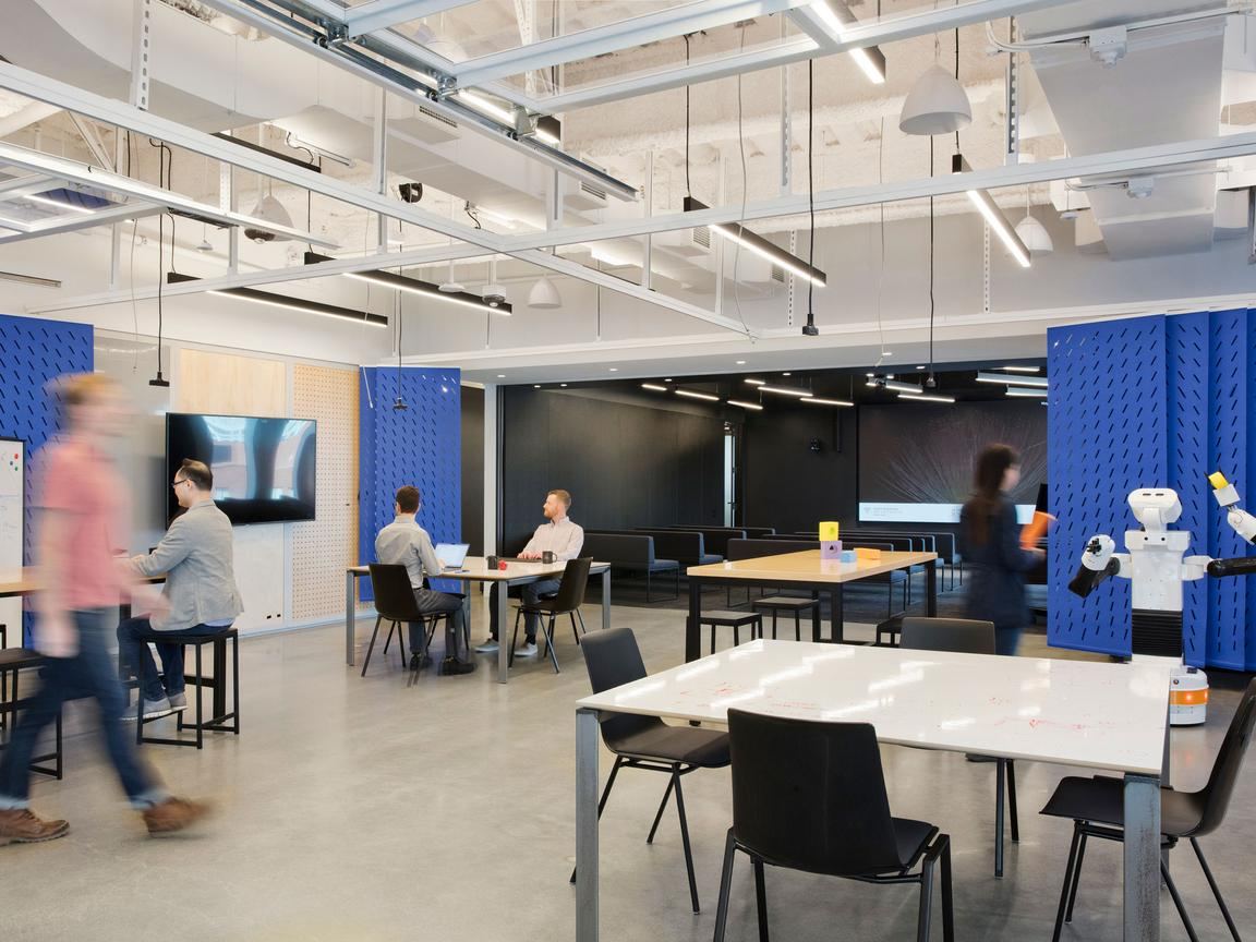 Collaboration room with movable tables, a large display and blue acoustic panels