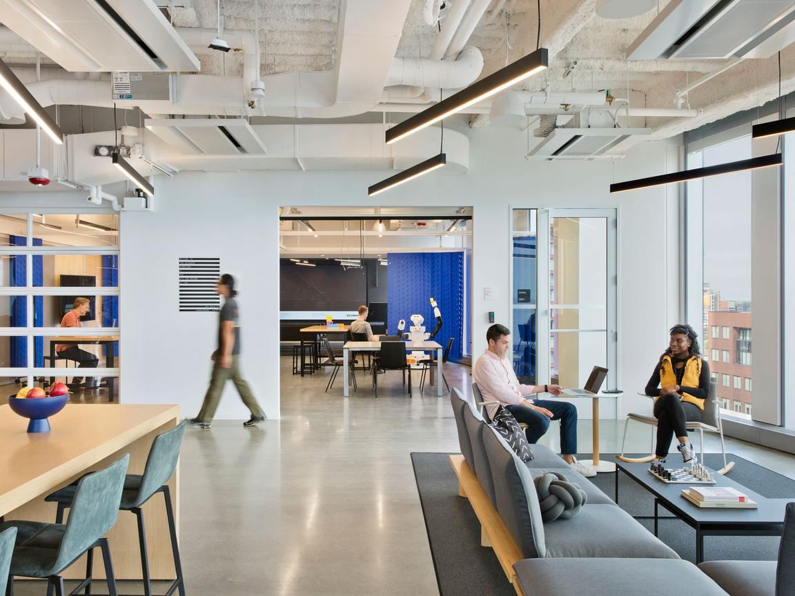 Lounge area with soft seating and a high table beside floor-to-ceiling windows